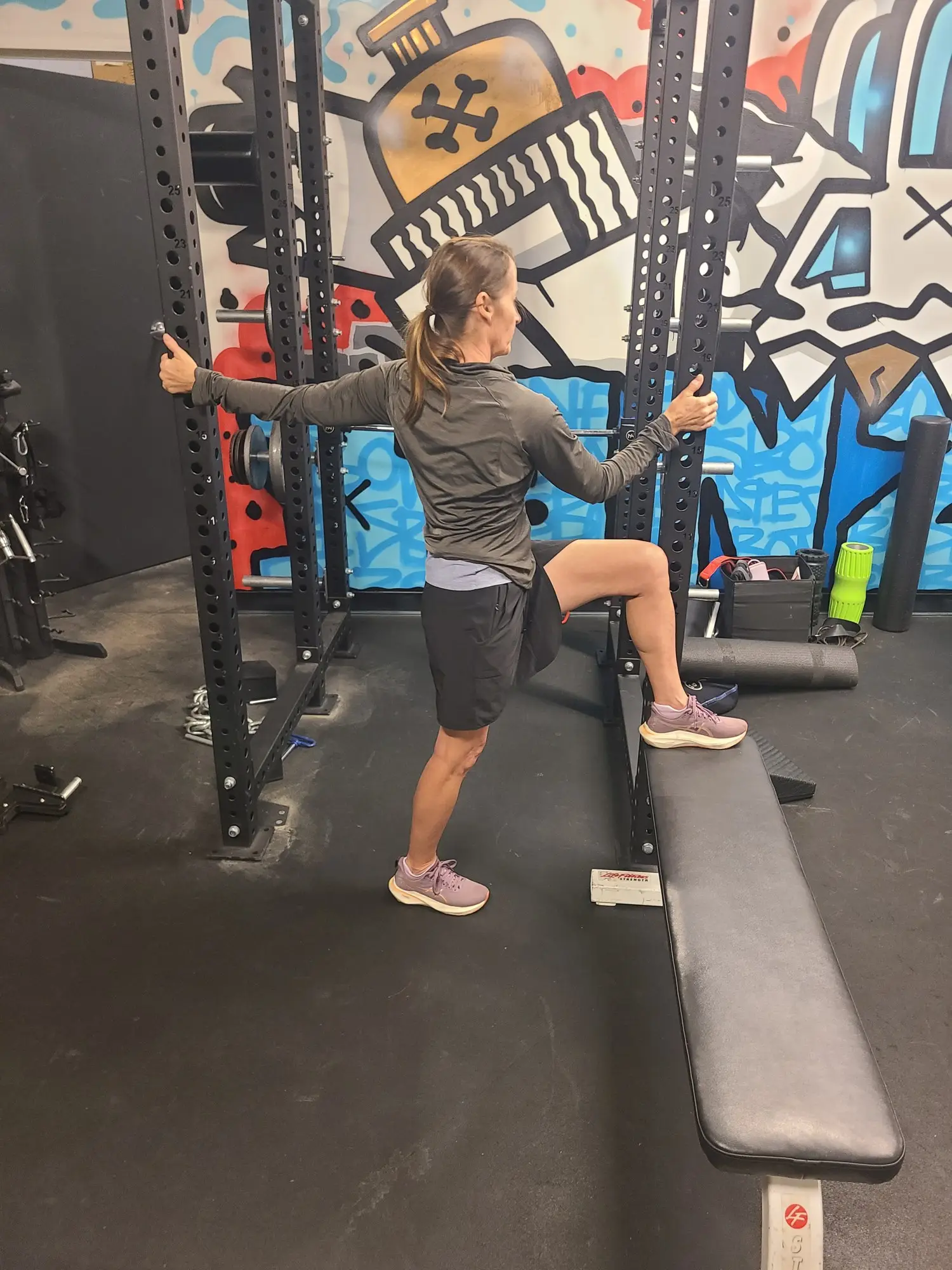 A client doing a step-up in the downtown Denver studio, back to the camera, coached by Jamie Atlas, personal trainer