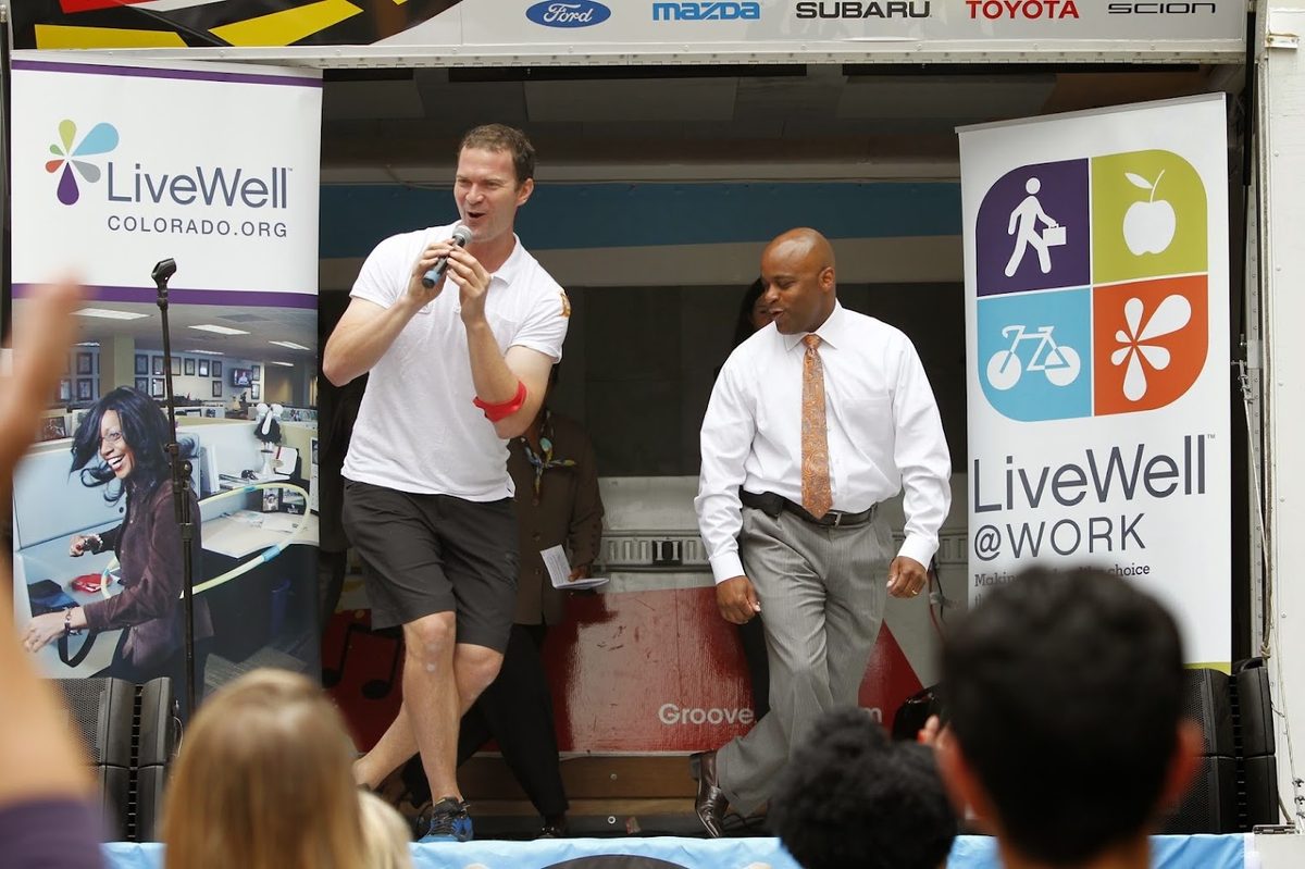 Jamie Atlas speaking on stage at a LiveWell Colorado workplace wellness event in downtown Denver