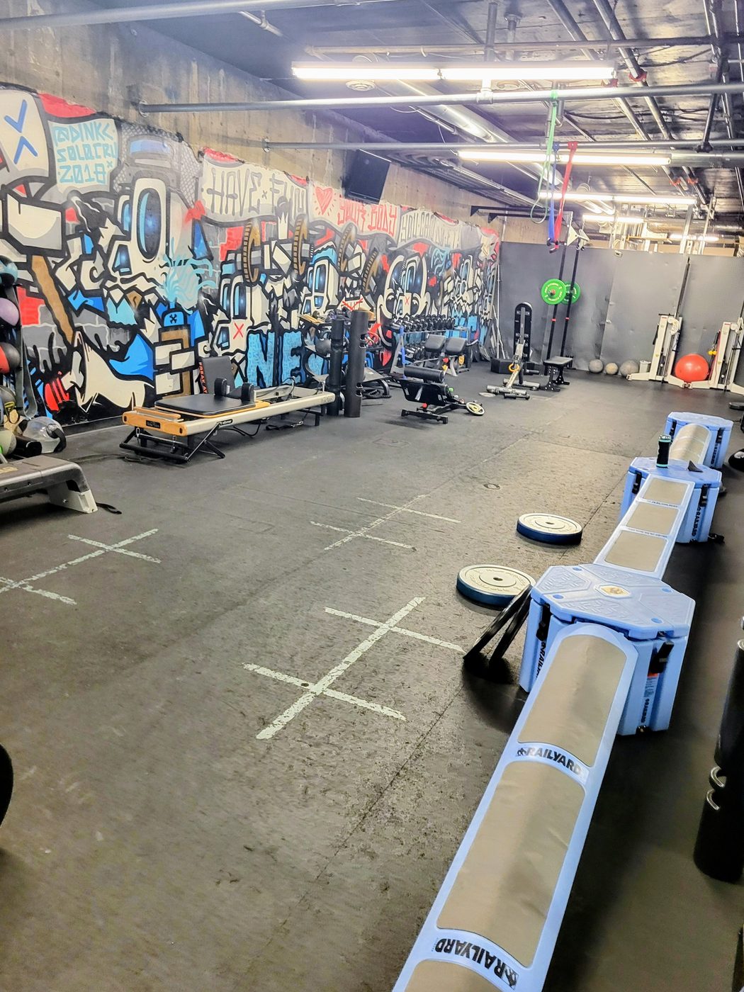The main training floor of the Jamie Atlas studio, with its graffiti mural wall, Pilates reformer and free-weight area